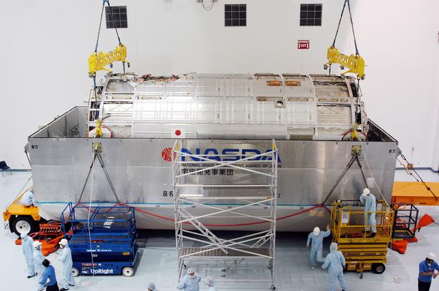 NASA image: KENNEDY SPACE CENTER, FLA. -  In the Space Station Processing Facility, an overhead crane begins to lift the Japanese Experiment Module (JEM) pressure module out of the shipping canister to move it to a work stand.  A research laboratory, the pressurized module is the first element of the JEM, named "Kibo" (Hope), to be delivered to KSC.   The National Space Development Agency of Japan (NASDA) developed the laboratory at the Tsukuba Space Center near Tokyo and is Japan's primary contribution to the Station. It will enhance the unique research capabilities of the orbiting complex by providing an additional environment for astronauts to conduct science experiments.  The JEM also includes an exposed facility (platform) for space environment experiments, a robotic manipulator system, and two logistics modules. The various JEM components will be  assembled in space over the course of three Shuttle missions.