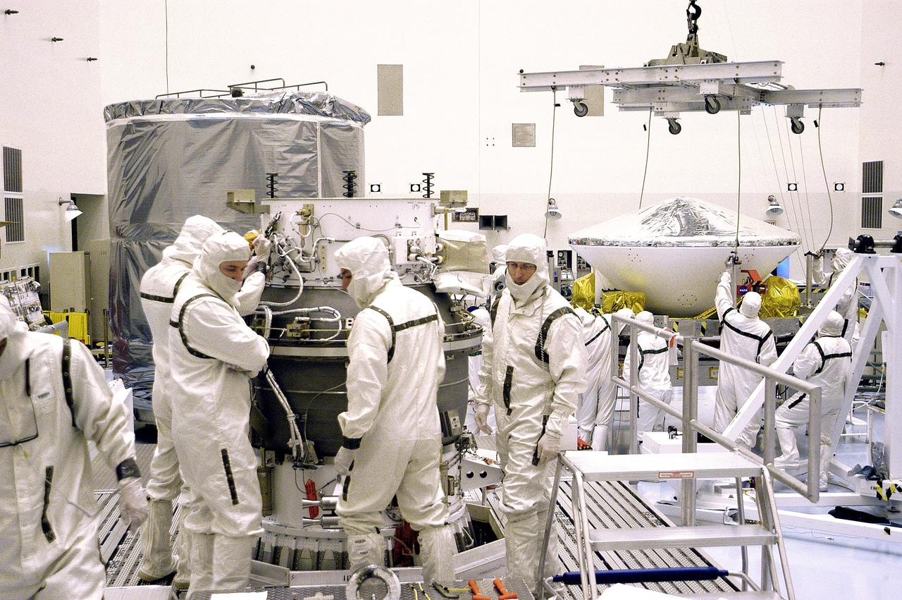 KENNEDY SPACE CENTER, FLA. - In the background, right, workers in the Payload Hazardous Servicing Facility get ready to lift Mars Exploration Rover 1 (MER-B) to the third stage of the Delta rocket (foreground) for mating.  The second of twin rovers being sent to Mars, it is equipped with a robotic arm, a drilling tool, three spectrometers, and four pairs of cameras that allow it to have a human-like, 3D view of the terrain. Each rover could travel as far as 100 meters in one day to act as Mars scientists' eyes and hands, exploring an environment where humans can't yet go.  MER-B is scheduled to launch from Launch Pad 17-B, Cape Canaveral Air Force Station, June 26 at one of two available times,  12:27:31 a.m. EDT or 1:08:45 a.m. EDT.