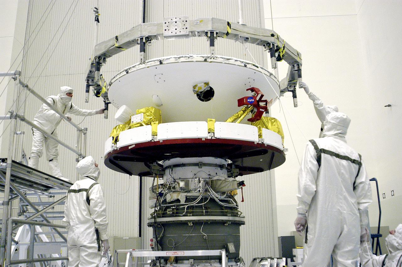 KENNEDY SPACE CENTER, FLA. -  In the Payload Hazardous Servicing Facility, workers check the connections after the Mars Exploration Rover 1 (MER-B) above was mated with the third stage of the Delta rocket below.  The second of twin rovers being sent to Mars, it is equipped with a robotic arm, a drilling tool, three spectrometers, and four pairs of cameras that allow it to have a human-like, 3D view of the terrain. Each rover could travel as far as 100 meters in one day to act as Mars scientists' eyes and hands, exploring an environment where humans can't yet go.  MER-B is scheduled to launch from Launch Pad 17-B, Cape Canaveral Air Force Station, June 26 at one of two available times,  12:27:31 a.m. EDT or 1:08:45 a.m. EDT.