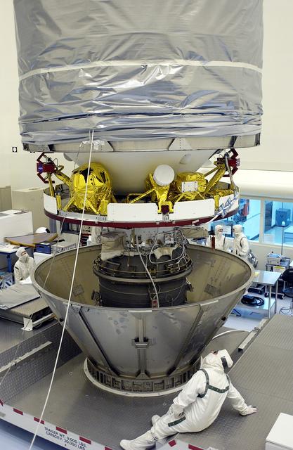 NASA image: KENNEDY SPACE CENTER, FLA. - In the Payload Hazardous Servicing Facility, the cylindrical payload canister is lowered around Mars Exploration Rover 1 (MER-B).  Once secure inside the canister, the rover will be transported to Launch Complex 17-B, Cape Canaveral Air Force Station, for mating with the Delta rocket.  The second of twin rovers being sent to Mars, it is equipped with a robotic arm, a drilling tool, three spectrometers, and four pairs of cameras that allow it to have a human-like, 3D view of the terrain. Each rover could travel as far as 100 meters in one day to act as Mars scientists' eyes and hands, exploring an environment where humans can't yet go.  MER-B is scheduled to launch from Pad 17-B June 26 at one of two available times,  12:27:31 a.m. EDT or 1:08:45 a.m. EDT.