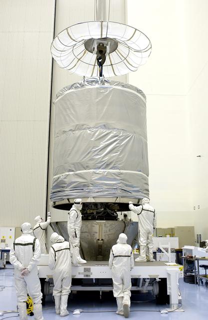 NASA image: KENNEDY SPACE CENTER, FLA. - In the Payload Hazardous Servicing Facility, workers maneuver the cylindrical payload canister into place around Mars Exploration Rover 1 (MER-B).  Once secure inside the canister, the rover will be transported to Launch Complex 17-B, Cape Canaveral Air Force Station, for mating with the Delta rocket.  The second of twin rovers being sent to Mars, it is equipped with a robotic arm, a drilling tool, three spectrometers, and four pairs of cameras that allow it to have a human-like, 3D view of the terrain. Each rover could travel as far as 100 meters in one day to act as Mars scientists' eyes and hands, exploring an environment where humans can't yet go.  MER-B is scheduled to launch from Pad 17-B June 26 at one of two available times,  12:27:31 a.m. EDT or 1:08:45 a.m. EDT.