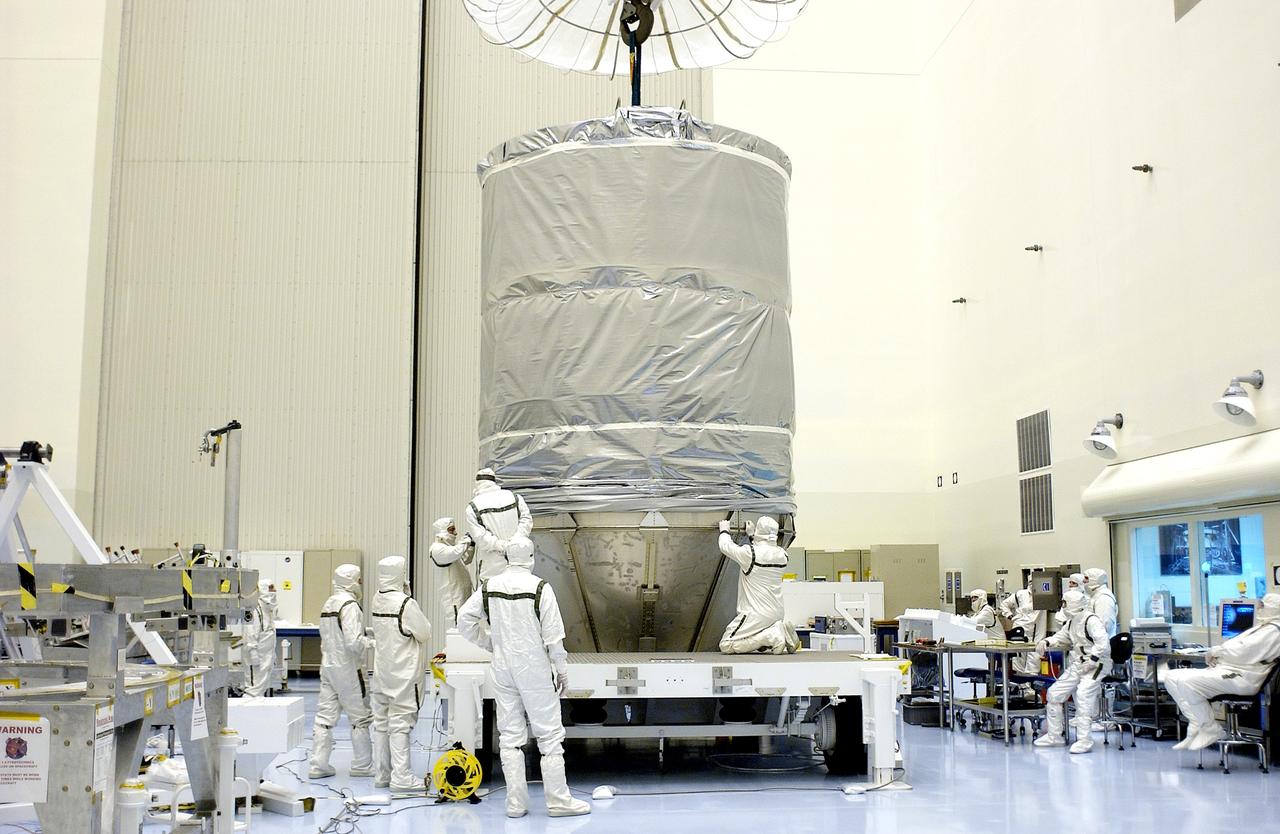 KENNEDY SPACE CENTER, FLA. - In the Payload Hazardous Servicing Facility, workers secure the cylindrical payload canister to the lower panels surrounding Mars Exploration Rover 1 (MER-B).  Once secure inside the canister, the rover will be transported to Launch Complex 17-B, Cape Canaveral Air Force Station, for mating with the Delta rocket.  The second of twin rovers being sent to Mars, it is equipped with a robotic arm, a drilling tool, three spectrometers, and four pairs of cameras that allow it to have a human-like, 3D view of the terrain. Each rover could travel as far as 100 meters in one day to act as Mars scientists' eyes and hands, exploring an environment where humans can't yet go.  MER-B is scheduled to launch from Pad 17-B June 26 at one of two available times,  12:27:31 a.m. EDT or 1:08:45 a.m. EDT.