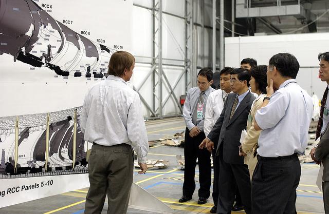 NASA image: KENNEDY SPACE CENTER, FLA. -    Shuttle Launch Director Mike Leinbach (left) explains recovery and reconstruction efforts of Columbia to the Executive Director of NASDA Koji Yamamoto (second from left) and others visiting the Columbia Debris Hangar.   Mr. Yamamoto is at KSC for a welcome ceremony involving the arrival of the newest Space Station module, the Japanese Experiment Module/pressurized module.