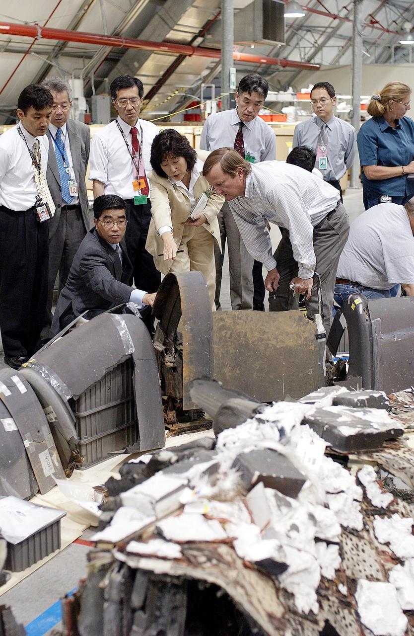 KENNEDY SPACE CENTER, FLA. -  On a KSC visit, Executive Director of NASDA Koji Yamamoto (kneeling, left) reaches out to a piece of Columbia debris in the Columbia Debris Hangar.  At right is Shuttle Launch Director Mike Leinbach, who is explaining recovery and reconstruction efforts.  Mr. Yamamoto is at KSC for a welcome ceremony involving the arrival of the newest Space Station module, the Japanese Experiment Module/pressurized module.
