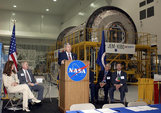 NASA image: KENNEDY SPACE CENTER, FLA. -   NASA's Michael C. Kostelnik, deputy associate administrator for International Space Station and Shuttle Programs, speaks to guests and the media gathered in the Space Station Processing Facility for a ceremony to highlight the arrival of two major components of the International Space Station.  NASA's Node 2, built by the European Space Agency (ESA) in Italy arrived at KSC on June 1. It will be the next pressurized module installed on the Station. The pressurized module of the Japanese Experiment Module (JEM), named "Kibo" (Hope) arrived at KSC on June 4. It is Japan's primary contribution to the Station. The ceremony held today included the official transfer of ownership signing of Node 2 between the ESA and NASA.. Emceed by Lisa Malone (far left),  deputy director of External Relations and Business Development at KSC, the ceremony also included these speakers: Center Director Roy Bridges Jr. (second from left); William Gerstenmaier, International Space Station Program manager; Alan Thirkettle, International Space Station Program manager for Node 2, ESA; Andrea Lorenzoni, International Space Station Program manager for Node 2, Italian Space Agency; and Kuniaki Shiraki, JEM Project manager, National Aerospace and Development Agency of Japan.
