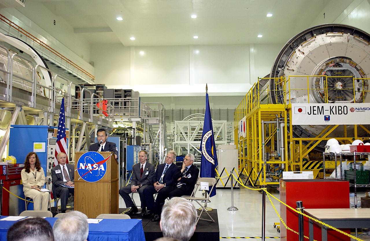 KENNEDY SPACE CENTER, FLA. - Kuniaki Shiraki, JEM Project manager, National Aerospace and Development Agency of Japan,  speaks to guests and the media gathered in the Space Station Processing Facility at a ceremony highlighting the arrival of two major components of the International Space Station.  NASA's Node 2, built by the European Space Agency (ESA) in Italy, arrived at KSC on June 1. It will be the next pressurized module installed on the Station. The pressurized module (above right)  of the Japanese Experiment Module (JEM),  named "Kibo" (Hope), arrived at KSC on June 4. It is Japan's primary contribution to the Station. The ceremony held today included the official transfer of ownership signing of Node 2 between the ESA and NASA.. Emceed by Lisa Malone (far left), deputy director of External Relations and Business Development at KSC, the ceremony also included these speakers: Center Director Roy Bridges Jr. (second from left); NASA’s Michael C. Kostelnik, deputy associate administrator for International Space Station and Shuttle Programs and William Gerstenmaier, International Space Station Program manager ; Alan Thirkettle, International Space Station Program manager for Node 2, ESA; and Andrea Lorenzoni, International Space Station Program manager for Node 2, Italian Space Agency.