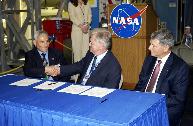 NASA image: KENNEDY SPACE CENTER, FLA. - At ceremony highlighting the arrival of two major components of the International Space Station, Node 2 and the Japanese Experiment Module (JEM), ownership of Node 2 was officially transferred between the European Space Agency and NASA.  Shaking hands after the signing are Andrea Lorenzoni, International Space Station Program manager for Node 2, Italian Space Agency; and Alan Thirkettle, International Space Station Program manager for Node 2, European Space Agency (ESA).  At right is NASA’s Michael C. Kostelnik, deputy associate administrator for International Space Station and Shuttle Programs.  NASA's Node 2, built by ESA in Italy, arrived at KSC on June 1. It will be the next pressurized module installed on the Station. The pressurized module of the Japanese Experiment Module (JEM),  named "Kibo" (Hope), arrived at KSC on June 4. It is Japan's primary contribution to the Station. Emceed by Lisa Malone, deputy director of External Relations and Business Development at KSC, the ceremony also included these speakers: Center Director Roy Bridges Jr.; NASA’s William Gerstenmaier, International Space Station Program manager; and Kuniaki Shiraki, JEM Project manager, National Aerospace and Development Agency of Japan.