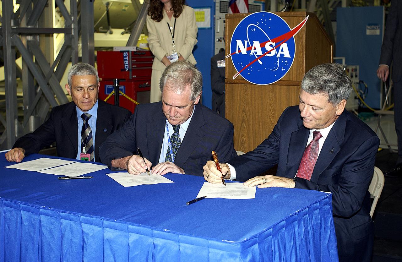 KENNEDY SPACE CENTER, FLA. - Alan Thirkettle (center), International Space Station Program manager for Node 2, European Space Agency (ESA); and NASA’s Michael C. Kostelnik (right), deputy associate administrator for International Space Station and Shuttle Programs, sign documents officially transferring ownership of Node 2 between the ESA and NASA.  At left, also part of the signing, is Andrea Lorenzoni (left), International Space Station Program manager for Node 2, Italian Space Agency.  NASA's Node 2, built by ESA in Italy, arrived at KSC on June 1. It will be the next pressurized module installed on the Station. The pressurized module of the Japanese Experiment Module (JEM),  named "Kibo" (Hope), arrived at KSC on June 4. It is Japan's primary contribution to the Station. Emceed by Lisa Malone, deputy director of External Relations and Business Development at KSC, the ceremony also included these speakers: Center Director Roy Bridges Jr.; NASA’s William Gerstenmaier, International Space Station Program manager; and Kuniaki Shiraki, JEM Project manager, National Aerospace and Development Agency of Japan.