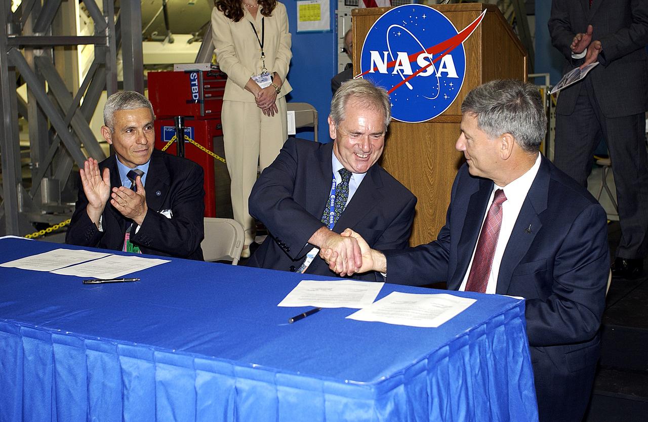 KENNEDY SPACE CENTER, FLA. - At a ceremony highlighting the arrival of two major components of the International Space Station, Node 2 and the Japanese Experiment Module (JEM), ownership of Node 2 was officially transferred between the European Space Agency (ESA) and NASA.  Shaking hands after the signing are Alan Thirkettle (center), International Space Station Program manager for Node 2, ESA; and NASA’s Michael C. Kostelnik (right), deputy associate administrator for International Space Station and Shuttle Programs.  At left, also part of the signing, is Andrea Lorenzoni (left), International Space Station Program manager for Node 2, Italian Space Agency.  NASA's Node 2, built by ESA in Italy, arrived at KSC on June 1. It will be the next pressurized module installed on the Station. The pressurized module of the Japanese Experiment Module (JEM),  named "Kibo" (Hope), arrived at KSC on June 4. It is Japan's primary contribution to the Station. Emceed by Lisa Malone, deputy director of External Relations and Business Development at KSC, the ceremony also included these speakers: Center Director Roy Bridges Jr.; NASA’s William Gerstenmaier, International Space Station Program manager; and Kuniaki Shiraki, JEM Project manager, National Aerospace and Development Agency of Japan.
