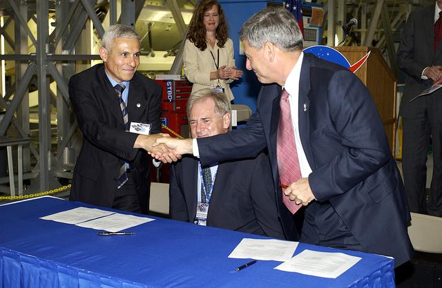 NASA image: KENNEDY SPACE CENTER, FLA. - At a ceremony highlighting the arrival of two major components of the International Space Station, Node 2 and the Japanese Experiment Module (JEM), ownership of Node 2 was officially transferred between the European Space Agency (ESA) and NASA.  Shaking hands after the signing are (left) Andrea Lorenzoni, International Space Station Program manager for Node 2, Italian Space Agency, and (right) NASA’s Michael C. Kostelnik (right), deputy associate administrator for International Space Station and Shuttle Programs.  Also part of the signing is (center) Alan Thirkettle (center), International Space Station Program manager for Node 2, European Space Agency.  NASA's Node 2, built by ESA in Italy, arrived at KSC on June 1. It will be the next pressurized module installed on the Station. The pressurized module of the Japanese Experiment Module (JEM),  named "Kibo" (Hope), arrived at KSC on June 4. It is Japan's primary contribution to the Station. Emceed by Lisa Malone (background, left),  deputy director of External Relations and Business Development at KSC, the ceremony also included these speakers: Center Director Roy Bridges Jr.; NASA’s William Gerstenmaier, International Space Station Program manager; and Kuniaki Shiraki, JEM Project manager, National Aerospace and Development Agency of Japan.