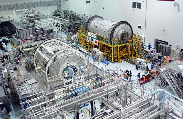 NASA image: KENNEDY SPACE CENTER, FLA. -  International Space Station elements being processed for launch on upcoming Space Shuttle flights, including the U.S. Node 2 and the Japanese Experiment Module (JEM) pressurized module, line the walls of the high bay in the Space Station Processing Facility. NASA's Node 2, built by the European Space Agency (ESA) in Italy, arrived at KSC on June 1. It will be the next pressurized module installed on the Station. The JEM pressurized module, named "Kibo" (Hope), arrived at KSC on June 4. It is Japan's primary contribution to the Station.