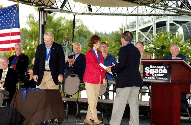 NASA image: KENNEDY SPACE CENTER, FLA. -  At the KSC Visitor Complex, former astronaut Robert L. Crippen (standing right) congratulates former astronaut Sally K. Ride at her induction ceremony into the U.S. Astronaut Hall of Fame. Also standing is former astronaut James A. Lovell.  Seated on the dais, from left, are former astronauts Gordon Cooper, Scott Carpenter, Buzz Aldrin, Walter Cunningham, Edgar B. Mitchell, and Fred W. Haise, all previously inducted into the Hall of Fame. Being inducted with Ride are Space Shuttle astronauts Daniel Brandenstein, Robert "Hoot" Gibson, and Story Musgrave. Conceived by six of the Mercury Program astronauts, the U.S. Astronaut Hall of Fame opened in 1990 to provide a place where space travelers could be remembered for their participation and accomplishments in the U.S. space program. The four new inductees join 48 previously honored astronauts from the ranks of the Gemini, Apollo, Skylab, Apollo-Soyuz, and Space Shuttle programs.