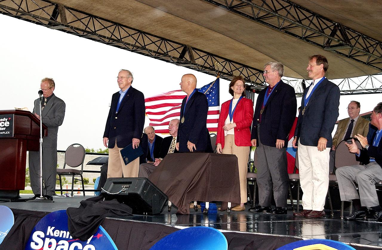 KENNEDY SPACE CENTER, FLA. -  At the KSC Visitor Complex, actor and Master of Ceremonies Lance Henriksen (at podium) introduces four newly inducted Space Shuttle astronauts to the audience at their induction ceremony into the U.S. Astronaut Hall of Fame. From left center, they are Story Musgrave, Sally K. Ride, Daniel Brandenstein, and Robert "Hoot" Gibson. Also standing, left, is former astronaut James A. Lovell.  Conceived by six of the Mercury Program astronauts, the U.S. Astronaut Hall of Fame opened in 1990 to provide a place where space travelers could be remembered for their participation and accomplishments in the U.S. space program. The four new inductees join 48 previously honored astronauts from the ranks of the Gemini, Apollo, Skylab, Apollo-Soyuz, and Space Shuttle programs.