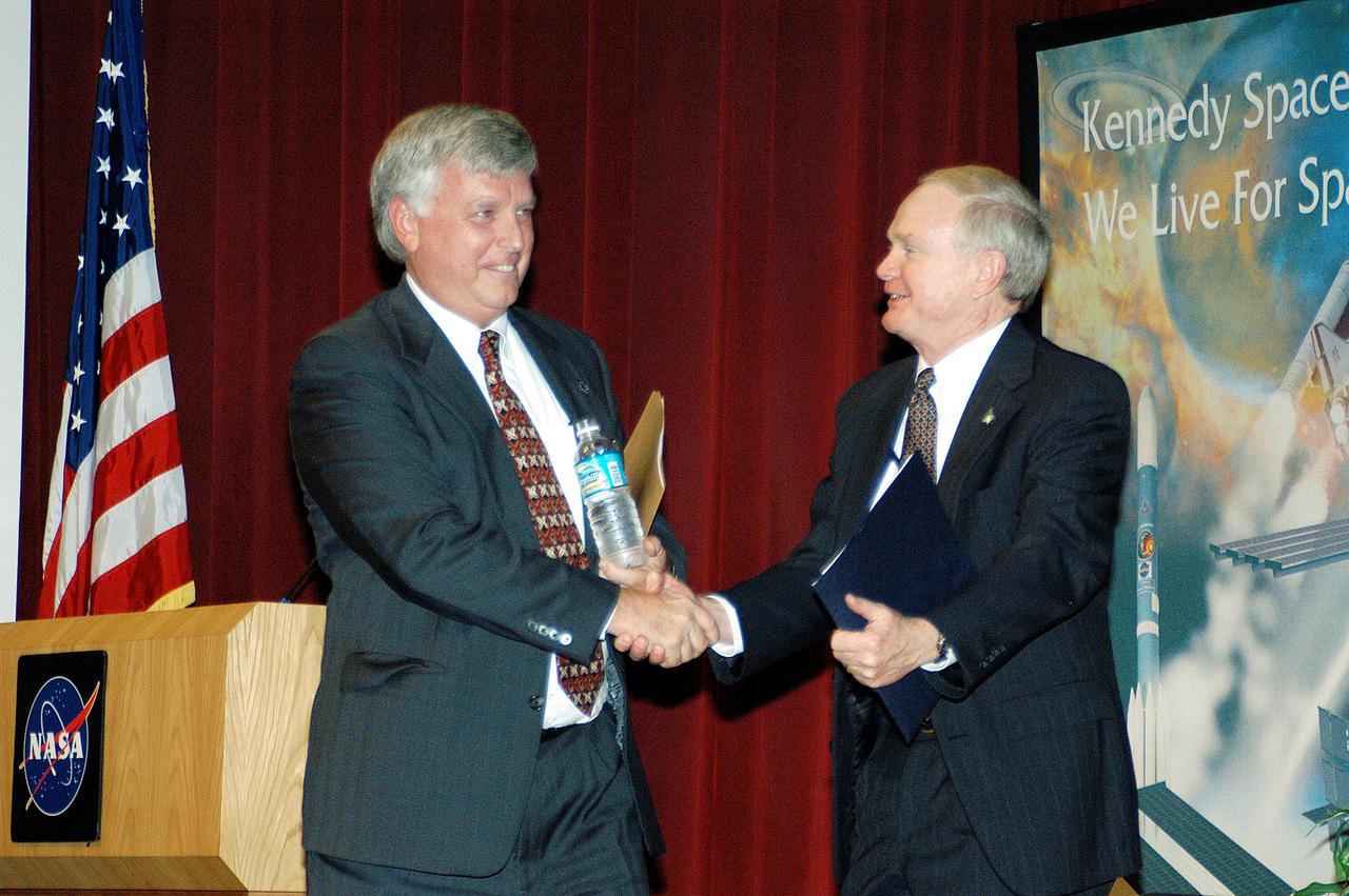 KENNEDY SPACE CENTER, FLA. -  KSC Deputy Director James W. Kennedy (left) and KSC Director Roy D. Bridges shake hands before a group of KSC employees assembled in the KSC Training Auditorium. The occasion is the announcement of Kennedy as the next director of the NASA Kennedy Space Center (KSC) in Florida. Kennedy has served as KSC's deputy director since November 2002. He will succeed Bridges, who was appointed on June 13 to lead NASA's Langley Research Center, Hampton, Va.