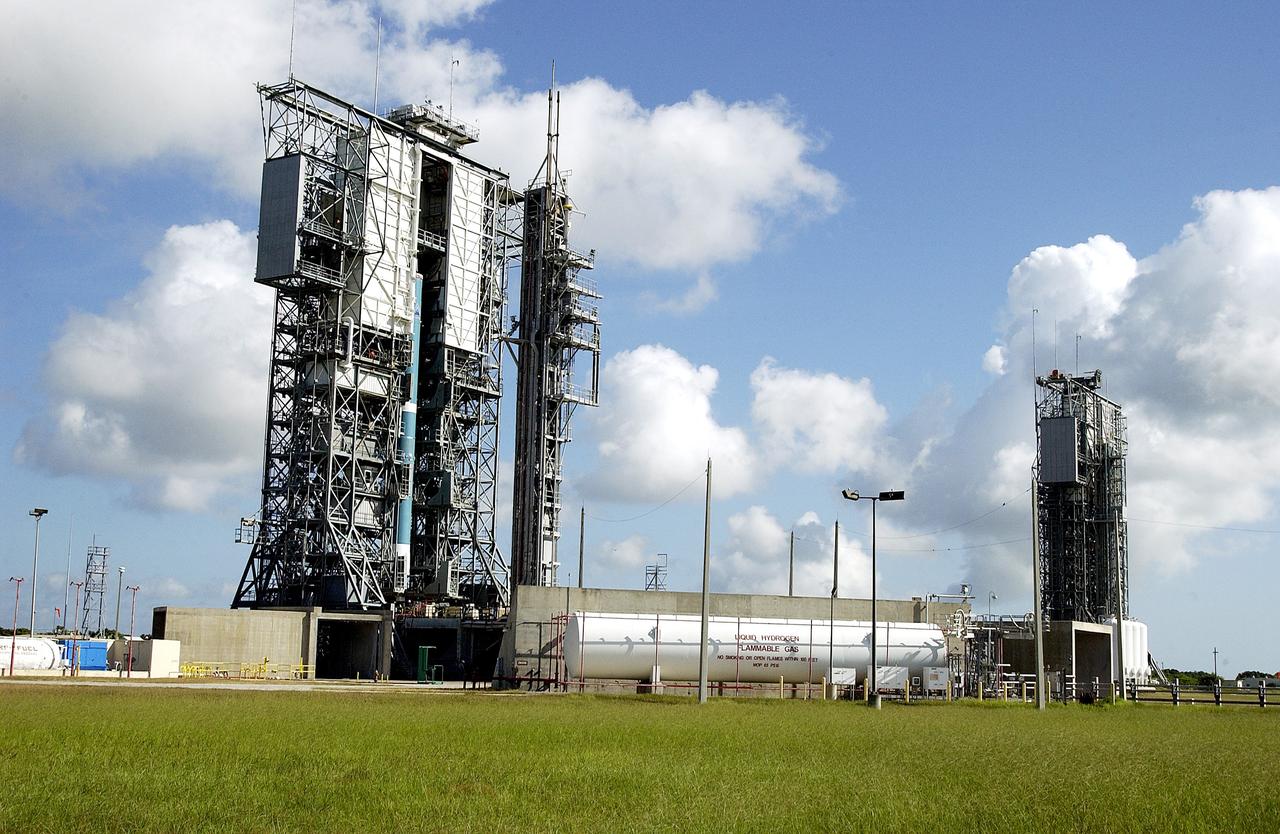 KENNEDY SPACE CENTER, FLA. -  On Launch Complex 17-B, Cape Canaveral Air Force Station, the first stage of a Delta II rocket is lifted up the mobile service tower.  In the background is pad 17-A.   The rocket is being erected to launch the Space InfraRed Telescope Facility (SIRTF).  Consisting of an 0.85-meter telescope and three cryogenically cooled science instruments, SIRTF is one of NASA's largest infrared telescopes to be launched.  SIRTF will obtain images and spectra by detecting the infrared energy, or heat, radiated by objects in space. Most of this infrared radiation is blocked by the Earth's atmosphere and cannot be observed from the ground.