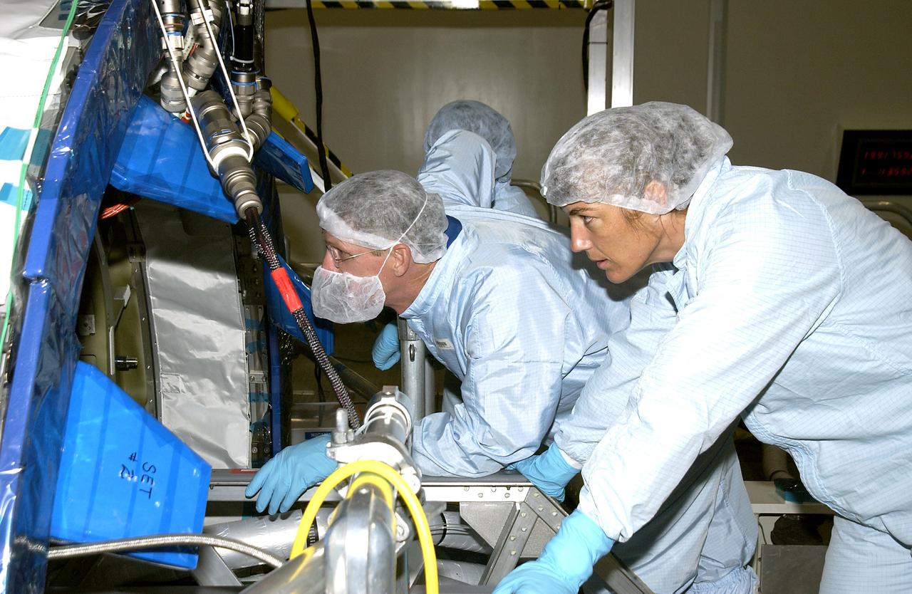 KENNEDY SPACE CENTER, FLA. - In the Space Station Processing Facility, STS-115 Mission Specialists Joseph Tanner (left) and Heidemarie Stefanyshyn-Piper (right) look over the Japanese Experiment Module (JEM) Pressurized Module located in the Space Station Processing Facility. Known as Kibo, the JEM consists of six components: two research facilities -- the Pressurized Module and Exposed Facility; a Logistics Module attached to each of them; a Remote Manipulator System; and an Inter-Orbit Communication System unit. Kibo also has a scientific airlock through which experiments are transferred and exposed to the external environment of space. The various components of JEM will be assembled in space over the course of three Space Shuttle missions. The STS-115 mission will deliver the second port truss segment, the P3/P4 Truss, to attach to the first port truss segment, the P1 Truss, as well as deploy solar array sets 2A and 4A.. The crew is scheduled to activate and check out the Solar Alpha Rotary Joint (SARJ) and deploy the P4 Truss radiator.
