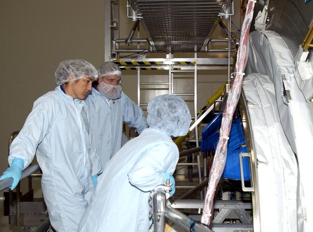 KENNEDY SPACE CENTER, FLA. - In the Space Station Processing Facility, STS-115 Mission Specialists Heidemarie Stefanyshyn-Piper (left) and Joseph Tanner (center) get ready to check out the Japanese Experiment Module (JEM) Pressurized Module. Known as Kibo, the JEM consists of six components: two research facilities -- the Pressurized Module and Exposed Facility; a Logistics Module attached to each of them; a Remote Manipulator System; and an Inter-Orbit Communication System unit. Kibo also has a scientific airlock through which experiments are transferred and exposed to the external environment of space. The various components of JEM will be assembled in space over the course of three Space Shuttle missions.   The STS-115  mission will deliver the second port truss segment, the P3/P4 Truss, to attach to the first port truss segment, the P1 Truss, as well as deploy solar array sets 2A and 4A..  The crew is scheduled to activate and check out the Solar Alpha Rotary Joint (SARJ) and deploy the P4 Truss radiator.