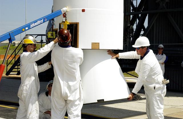 NASA image: KENNEDY SPACE CENTER, FLA. -   Workers on Launch Complex 17-B, Cape Canaveral Air Force Station, help steady a solid rocket booster (SRB) being lifted into the mobile service tower.  It is one of nine  46-inch-diameter, stretched SRBs that are being attached to the Delta II Heavy rocket that will launch the Space Infrared Telescope Facility (SIRTF).  Consisting of three cryogenically cooled science instruments and an 0.85-meter telescope, SIRTF is one of NASA's largest infrared telescopes to be launched.  SIRTF will obtain images and spectra by detecting the infrared energy, or heat, radiated by objects in space. Most of this infrared radiation is blocked by the Earth's atmosphere and cannot be observed from the ground.