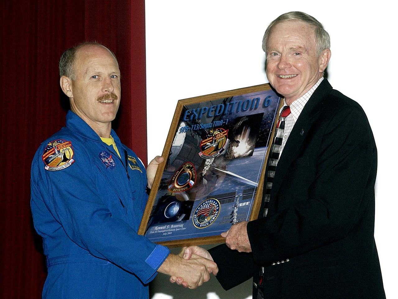 KENNEDY SPACE CENTER, FLA. - Expedition 6 Commander Ken Bowersox (left) accepts from Center Director Roy Bridges Jr. a framed graphic commemorating his stay on the International Space Station.  Bowersox spoke to KSC employees about his mission and residence on the Station from November 25, 2002, to May 3, 2003.