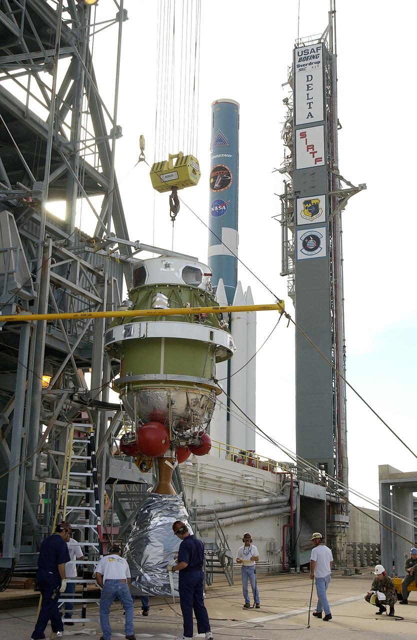 The second stage of the Delta II Heavy rocket is lifted up the mobile service tower on Launch Complex 17-B, Cape Canaveral Air Force Station for mating with the first stage (in the background) with its nine solid rocket boosters. The rocket will launch the Space Infrared Telescope Facility (SIRTF), currently scheduled for mid-August. SIRTF consists of three cryogenically cooled science instruments and an 0.85-meter telescope, and is one of NASA's largest infrared telescopes to be launched. SIRTF will obtain images and spectra by detecting the infrared energy, or heat, radiated by objects in space. Most of this infrared radiation is blocked by the Earth's atmosphere and cannot be observed from the ground.