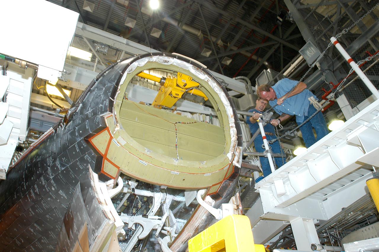 Workers look at orbiter Endeavour after the nose cap was removed for routine inspection. The nose cap is made of reinforced carbon-carbon (RCC). The RCC has an operating range of minus 250° F to about 3,000° F. 