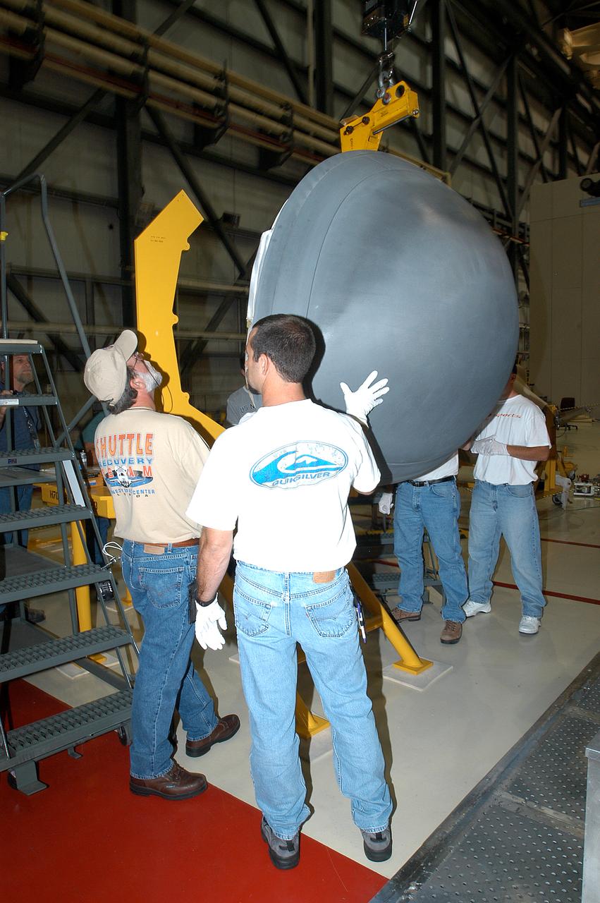 Workers watch as the nose cap of orbiter Endeavour is lowered after removal for routine inspection. The nose cap is made of reinforced carbon-carbon (RCC). The RCC has an operating range of minus 250° F to about 3,000° F. 