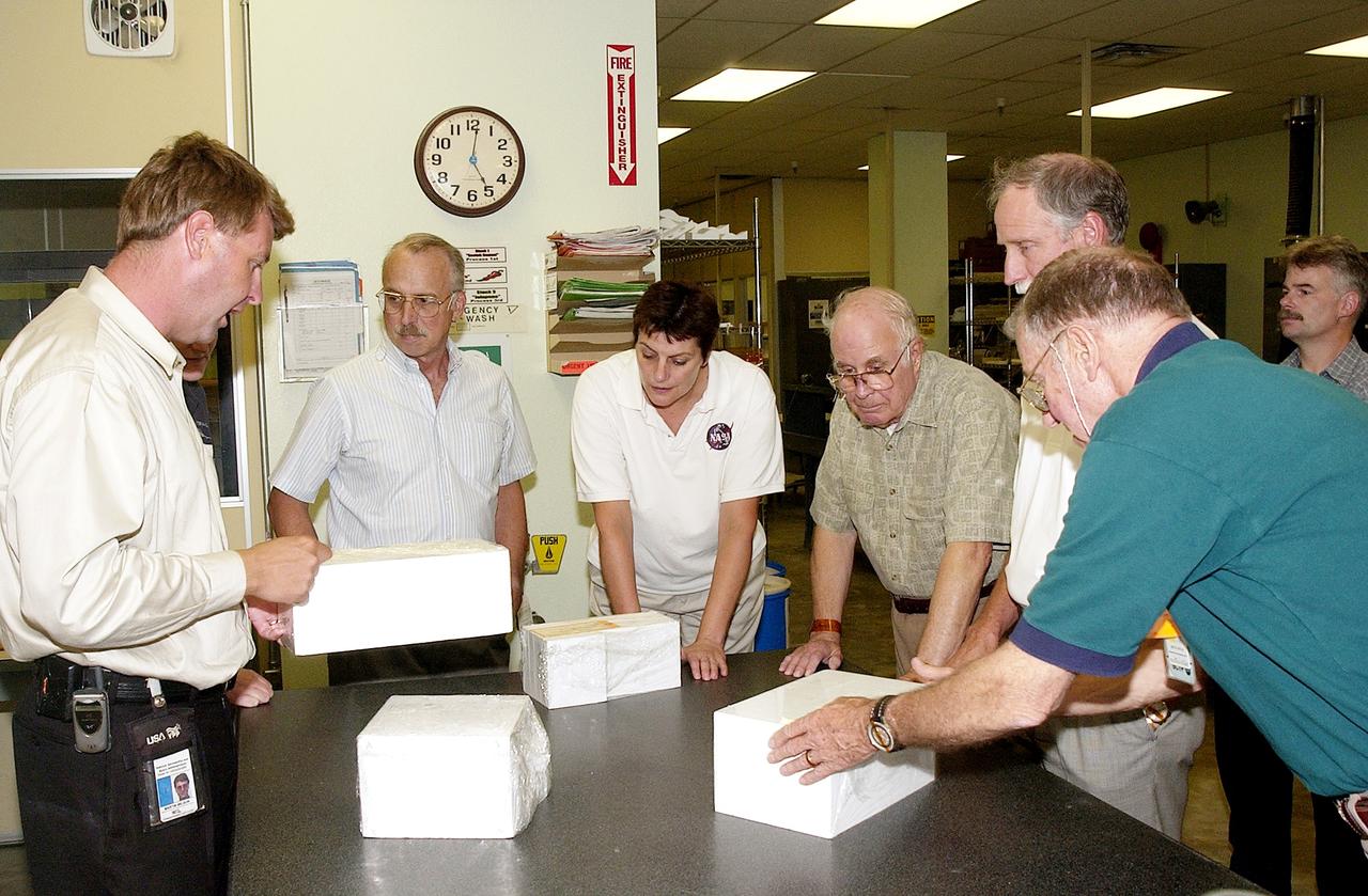 KENNEDY SPACE CENTER, FLA.  -  On a tour of the Tile Shop, members of the Stafford-Covey Return to Flight Task Group (SCTG) learn about PU-tiles, part of an orbiter’s Thermal Protection System.   At left is Martin Wilson, with United Space Alliance.  Others (left to right) around the table are James Adamson, Dr. Kathryn Clark, William Wegner, Richard Covey and Joe Engle.  Covey, former Space Shuttle commander, is co-chair of the  SCTG, along with Thomas P. Stafford, Apollo commander.  Chartered by NASA Administrator Sean O’Keefe, the task group will perform an independent assessment of NASA’s implementation of the final recommendations by the Columbia Accident Investigation Board.