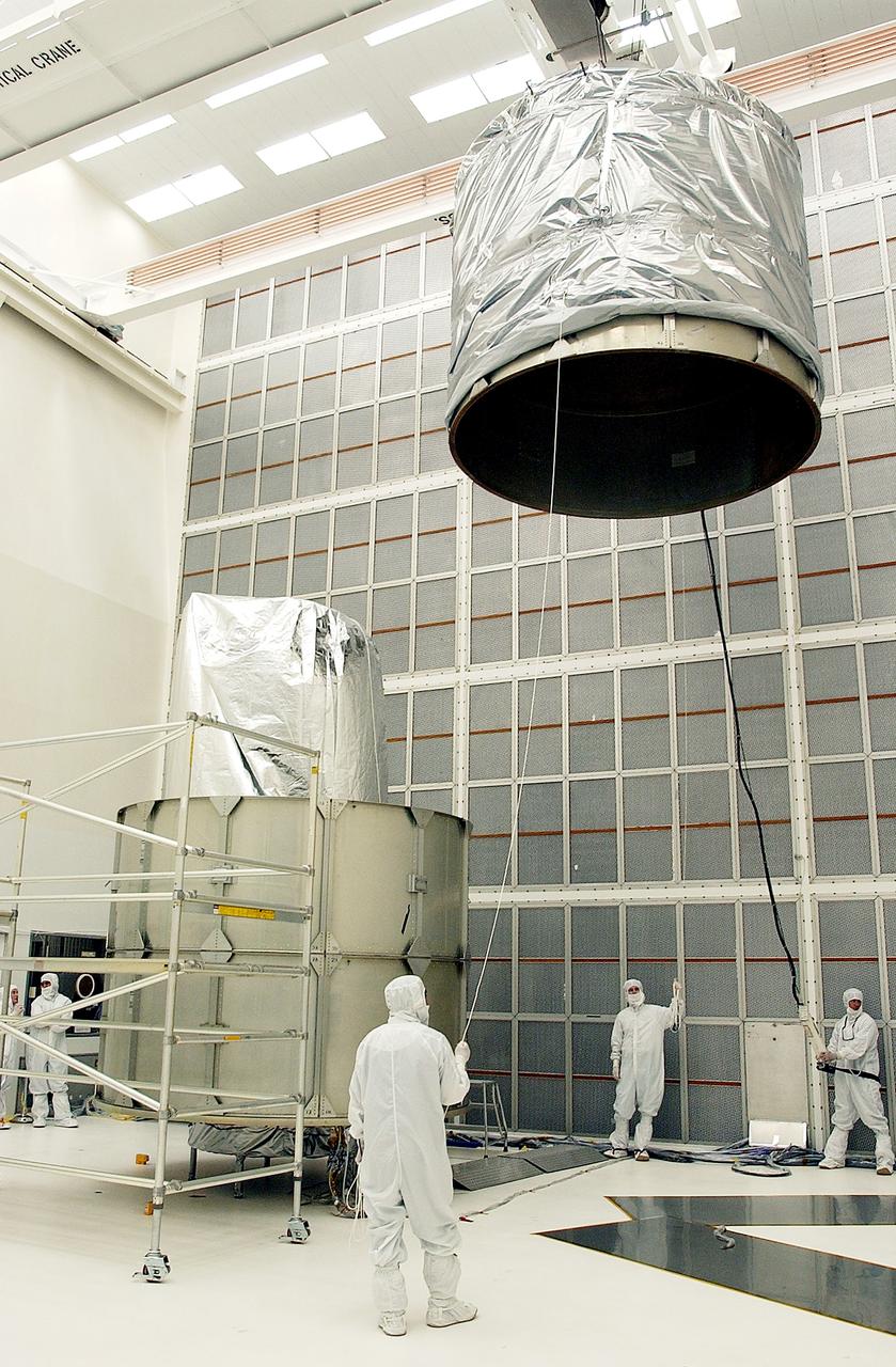 KENNEDY SPACE CENTER, FLA.  - Workers at Hangar A&E, Cape Canaveral Air Force Station, help guide the upper canister toward the Space Infrared Telescope Facility (SIRTF) at left.  After encapsulation is complete, the spacecraft will be transported to Launch Complex 17-B for mating with its launch vehicle, the Delta II rocket.   SIRTF consists of three cryogenically cooled science instruments and an 0.85-meter telescope, and is one of NASA's largest infrared telescopes to be launched.  SIRTF will obtain images and spectra by detecting the infrared energy, or heat, radiated by objects in space. Most of this infrared radiation is blocked by the Earth's atmosphere and cannot be observed from the ground.