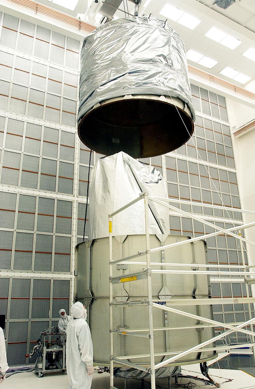 KENNEDY SPACE CENTER, FLA.  - Workers at Hangar A&E, Cape Canaveral Air Force Station, lower the upper canister toward the Space Infrared Telescope Facility (SIRTF) below.  After encapsulation is complete, the spacecraft will be transported to Launch Complex 17-B for mating with its launch vehicle, the Delta II rocket.   SIRTF consists of three cryogenically cooled science instruments and an 0.85-meter telescope, and is one of NASA's largest infrared telescopes to be launched.  SIRTF will obtain images and spectra by detecting the infrared energy, or heat, radiated by objects in space. Most of this infrared radiation is blocked by the Earth's atmosphere and cannot be observed from the ground.