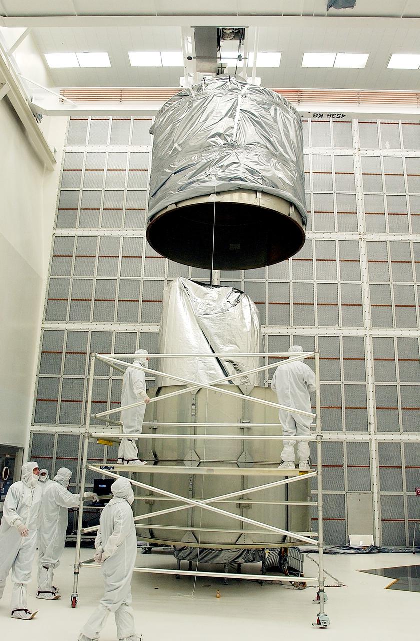 KENNEDY SPACE CENTER, FLA.  -  In Hangar A&E, Cape Canaveral Air Force Station, the upper canister is lowered toward the Space Infrared Telescope Facility (SIRTF) below.  After encapsulation is complete, the spacecraft will be transported to Launch Complex 17-B for mating with its launch vehicle, the Delta II rocket.   SIRTF consists of three cryogenically cooled science instruments and an 0.85-meter telescope, and is one of NASA's largest infrared telescopes to be launched.  SIRTF will obtain images and spectra by detecting the infrared energy, or heat, radiated by objects in space. Most of this infrared radiation is blocked by the Earth's atmosphere and cannot be observed from the ground.