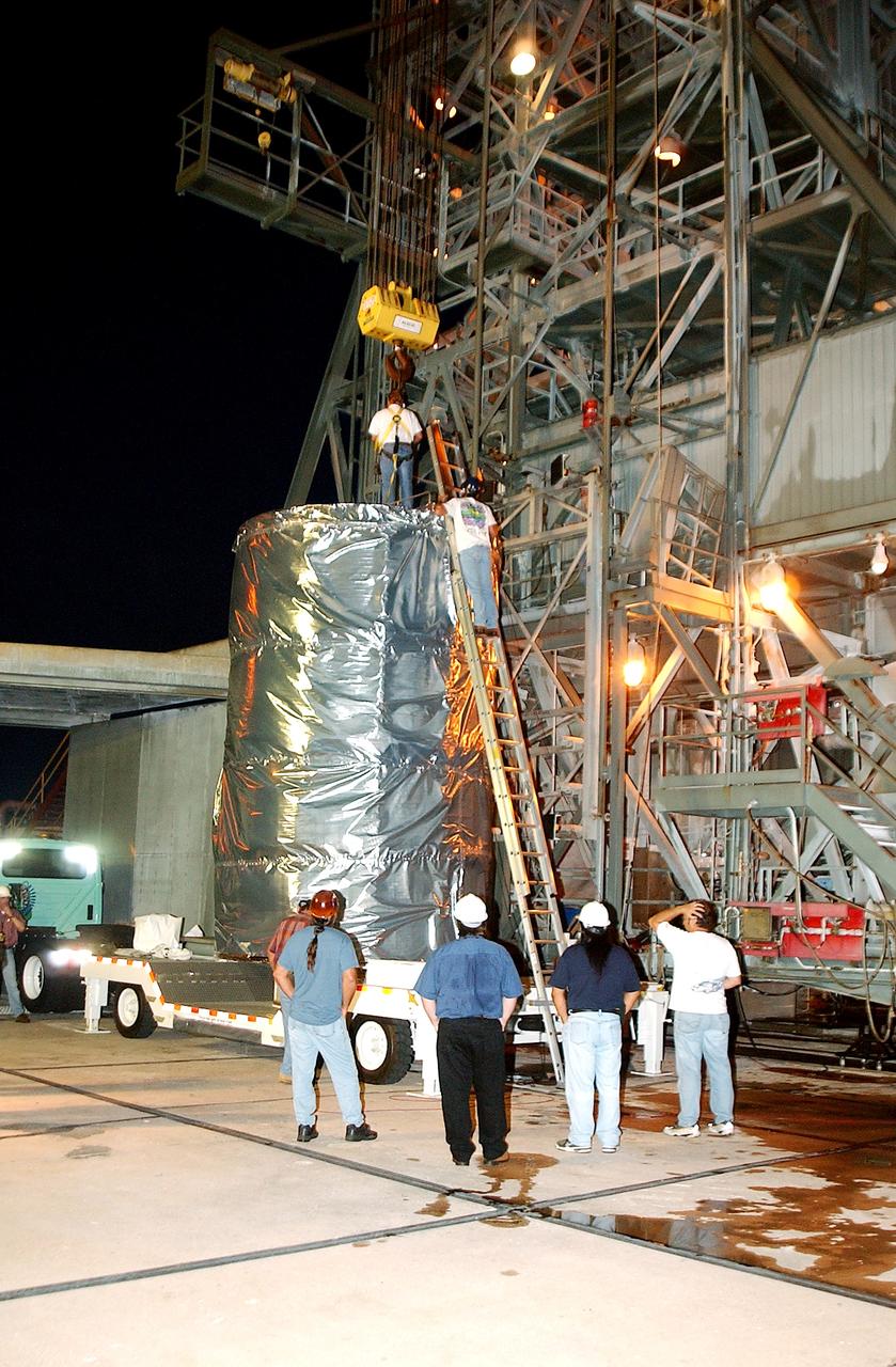 KENNEDY SPACE CENTER, FLA.  -  Before dawn, the Space Infrared Telescope Facility (SIRTF) is attached to an overhead crane that will lift it up the mobile service tower on Launch Pad 17-B, Cape Canaveral Air Force Station.  SIRTF will be attached to the Delta II rocket and encapsulated in its fairing before launch.   Consisting of three cryogenically cooled science instruments and an 0.85-meter telescope, SIRTF is one of NASA’s largest infrared telescopes to be launched.  It is the fourth and final element in NASA’s family of orbiting “Great Observatories.”  SIRTF will obtain images and spectra by detecting the infrared energy, or heat, radiated by objects in space. Most of this infrared radiation is blocked by the Earth's atmosphere and cannot be observed from the ground.