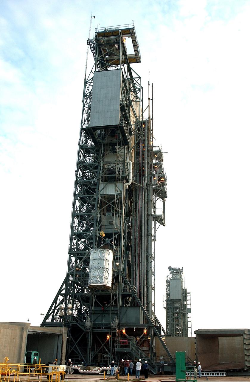 KENNEDY SPACE CENTER, FLA.  -  After dawn,  the Space Infrared Telescope Facility (SIRTF) is lifted up the mobile service tower on Launch Pad 17-B, Cape Canaveral Air Force Station.  SIRTF will be attached to the Delta II rocket and encapsulated in its fairing before launch.   Consisting of three cryogenically cooled science instruments and an 0.85-meter telescope, SIRTF is one of NASA’s largest infrared telescopes to be launched.  It is the fourth and final element in NASA’s family of orbiting “Great Observatories.”  SIRTF will obtain images and spectra by detecting the infrared energy, or heat, radiated by objects in space. Most of this infrared radiation is blocked by the Earth's atmosphere and cannot be observed from the ground.