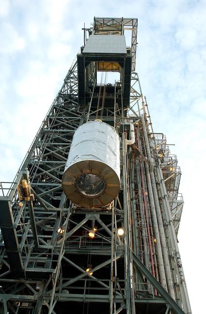 NASA image: KENNEDY SPACE CENTER, FLA.  -  Viewed from below, the Space Infrared Telescope Facility (SIRTF) is lifted up the mobile service tower on Launch Pad 17-B, Cape Canaveral Air Force Station.  SIRTF will be attached to the Delta II rocket and encapsulated in its fairing before launch.   Consisting of three cryogenically cooled science instruments and an 0.85-meter telescope, SIRTF is one of NASA’s largest infrared telescopes to be launched.  It is the fourth and final element in NASA’s family of orbiting “Great Observatories.”  SIRTF will obtain images and spectra by detecting the infrared energy, or heat, radiated by objects in space. Most of this infrared radiation is blocked by the Earth's atmosphere and cannot be observed from the ground.
