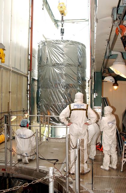 NASA image: KENNEDY SPACE CENTER, FLA.  -  Workers on the mobile service tower on Launch Pad 17-B, Cape Canaveral Air Force Station, watch as the Space Infrared Telescope Facility (SIRTF) clears the platform.   SIRTF will be attached to the Delta II rocket and encapsulated in its fairing before launch.   Consisting of three cryogenically cooled science instruments and an 0.85-meter telescope, SIRTF is one of NASA’s largest infrared telescopes to be launched.  It is the fourth and final element in NASA’s family of orbiting “Great Observatories.”  SIRTF will obtain images and spectra by detecting the infrared energy, or heat, radiated by objects in space. Most of this infrared radiation is blocked by the Earth's atmosphere and cannot be observed from the ground.