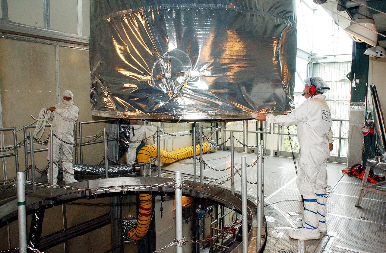 KENNEDY SPACE CENTER, FLA.  -  Workers on the mobile service tower on Launch Pad 17-B, Cape Canaveral Air Force Station, help guide the Space Infrared Telescope Facility (SIRTF) toward the opening in the foreground.  SIRTF will be attached to the Delta II rocket and encapsulated in its fairing before launch.   Consisting of three cryogenically cooled science instruments and an 0.85-meter telescope, SIRTF is one of NASA’s largest infrared telescopes to be launched.  It is the fourth and final element in NASA’s family of orbiting “Great Observatories.”  SIRTF will obtain images and spectra by detecting the infrared energy, or heat, radiated by objects in space. Most of this infrared radiation is blocked by the Earth's atmosphere and cannot be observed from the ground.