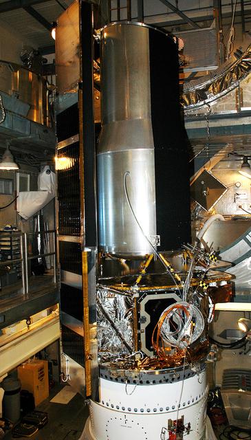 NASA image: KENNEDY SPACE CENTER, FLA.  - In the mobile service tower on Launch Pad 17-B, Cape Canaveral Air Force Station, the Space Infrared Telescope Facility (SIRTF) waits for encapsulation. SIRTF will obtain images and spectra by detecting the infrared energy, or heat, radiated by objects in space. Consisting of a 0.85-meter telescope and three cryogenically cooled science instruments, SIRTF will be the largest infrared telescope ever launched into space. It is the fourth and final element in NASA’s family of orbiting “Great Observatories.” Its highly sensitive instruments will give a unique view of the Universe and peer into regions of space that are hidden from optical telescopes.