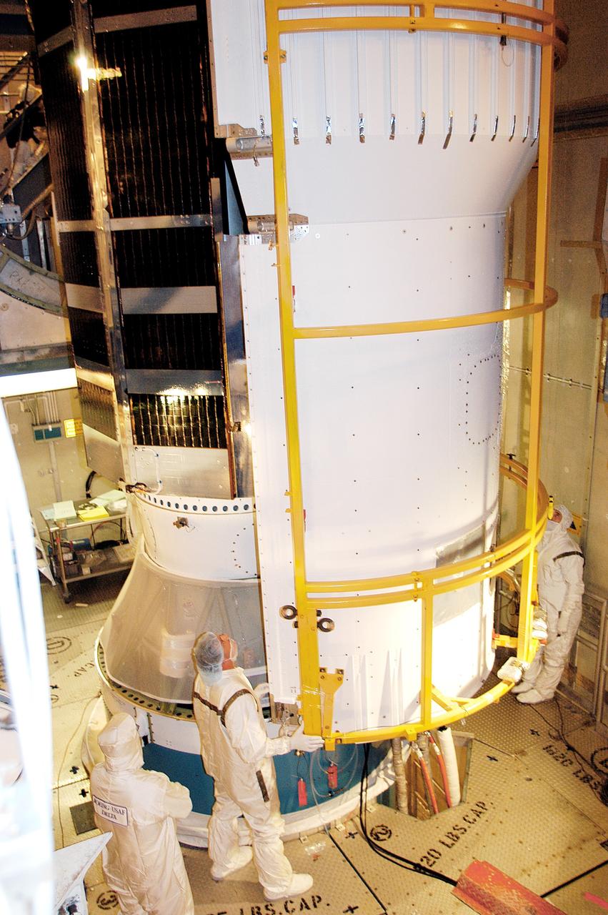 KENNEDY SPACE CENTER, FLA.  - In the mobile service tower on Launch Pad 17-B, Cape Canaveral Air Force Station, workers move the first half of the fairing around the Space Infrared Telescope Facility (SIRTF) behind it for encapsulation. SIRTF will obtain images and spectra by detecting the infrared energy, or heat, radiated by objects in space. Consisting of a 0.85-meter telescope and three cryogenically cooled science instruments, SIRTF will be the largest infrared telescope ever launched into space. It is the fourth and final element in NASA’s family of orbiting “Great Observatories.” Its highly sensitive instruments will give a unique view of the Universe and peer into regions of space that are hidden from optical telescopes.