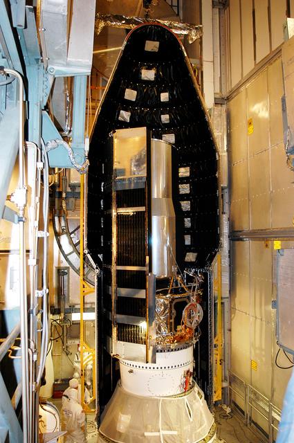 NASA image: KENNEDY SPACE CENTER, FLA.  - In the mobile service tower on Launch Pad 17-B, Cape Canaveral Air Force Station, the first half of the fairing is moved around the Space Infrared Telescope Facility (SIRTF). SIRTF will obtain images and spectra by detecting the infrared energy, or heat, radiated by objects in space. Consisting of a 0.85-meter telescope and three cryogenically cooled science instruments, SIRTF will be the largest infrared telescope ever launched into space. It is the fourth and final element in NASA’s family of orbiting “Great Observatories.” Its highly sensitive instruments will give a unique view of the Universe and peer into regions of space that are hidden from optical telescopes.