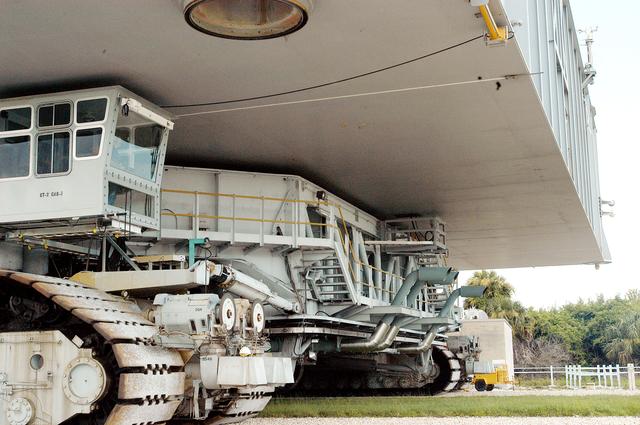 NASA image: KENNEDY SPACE CENTER, FLA.  -  A closeup of crawler-transporter (CT) number 2 shows the cab, at left, that recently underwent modifications.  The CT is transporting a Mobile Launch Platform (MLP) on a test run to the pad.  The CT moves Space Shuttle vehicles, situated on the MLP, between the VAB and launch pad.  Moving on four double-tracked crawlers, the CT uses a laser guidance system and a leveling system for the journey that keeps the top of a Space Shuttle vertical within plus- or minus-10 minutes of arc.  The system enables the CT-MLP-Shuttle to negotiate the ramp leading to the launch pads and keep the load level.  Unloaded, the CT weighs 6 million pounds.  Seen on top of the MLP are two tail service masts that support the fluid, gas and electrical requirements of the orbiter’s liquid oxygen and liquid hydrogen aft umbilicals.