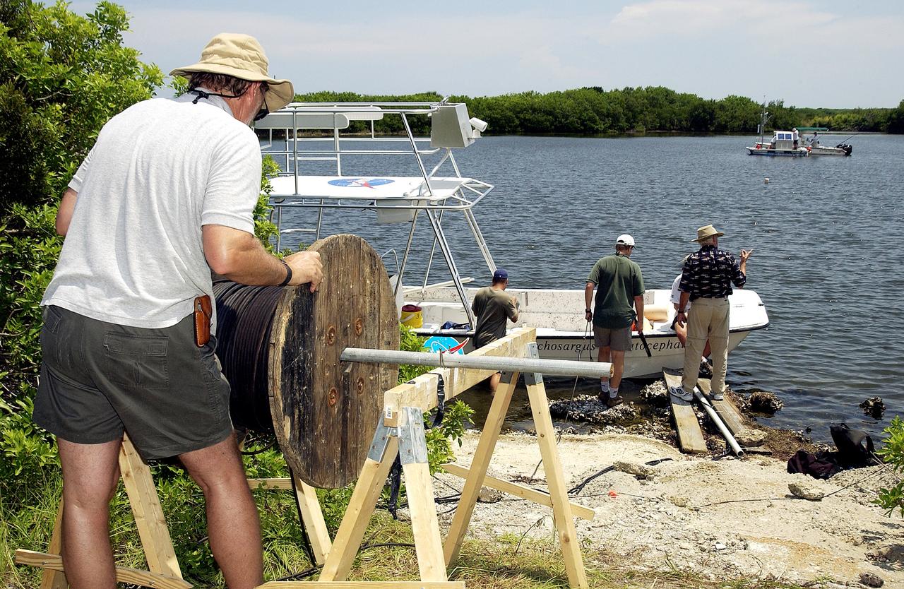 KENNEDY SPACE CENTER, FLA.  -  Research team members roll out acoustic cable to the water's edge during underwater acoustic research being conducted in the Launch Complex 39 turn basin.  Several government agencies, including NASA, NOAA, the Navy, the Coast Guard, and the Florida Fish and Wildlife Commission are involved in the testing. The research involves demonstrations of passive and active sensor technologies, with applications in fields ranging from marine biological research to homeland security. The work is also serving as a pilot project to assess the cooperation between the agencies involved. Equipment under development includes a passive acoustic monitor developed by NASA’s Jet Propulsion Laboratory, and mobile robotic sensors from the Navy’s Mobile Diving and Salvage Unit.