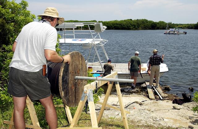 NASA image: KENNEDY SPACE CENTER, FLA.  -  Research team members roll out acoustic cable to the water's edge during underwater acoustic research being conducted in the Launch Complex 39 turn basin.  Several government agencies, including NASA, NOAA, the Navy, the Coast Guard, and the Florida Fish and Wildlife Commission are involved in the testing. The research involves demonstrations of passive and active sensor technologies, with applications in fields ranging from marine biological research to homeland security. The work is also serving as a pilot project to assess the cooperation between the agencies involved. Equipment under development includes a passive acoustic monitor developed by NASA’s Jet Propulsion Laboratory, and mobile robotic sensors from the Navy’s Mobile Diving and Salvage Unit.
