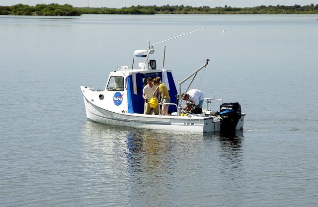 NASA image: KENNEDY SPACE CENTER, FLA.  -  Research team members aboard one of the watercraft being utilized to conduct underwater acoustic research in the Launch Complex 39 turn basin prepare to release some of the project's equipment into the water.  Several government agencies, including NASA, NOAA, the Navy, the Coast Guard, and the Florida Fish and Wildlife Commission are involved in the testing. The research involves demonstrations of passive and active sensor technologies, with applications in fields ranging from marine biological research to homeland security. The work is also serving as a pilot project to assess the cooperation between the agencies involved. Equipment under development includes a passive acoustic monitor developed by NASA’s Jet Propulsion Laboratory, and mobile robotic sensors from the Navy’s Mobile Diving and Salvage Unit.