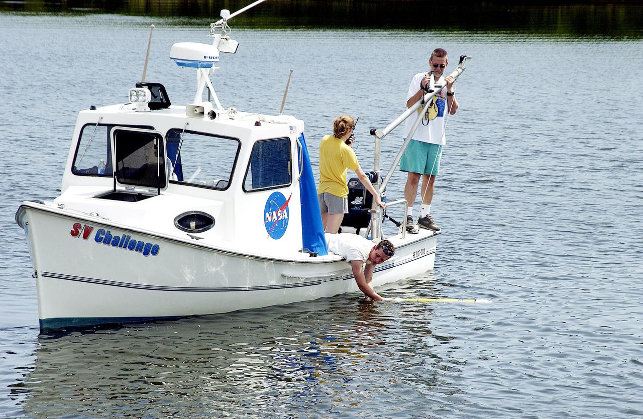 KENNEDY SPACE CENTER, FLA.  -  A research team member aboard one of the watercraft being utilized to conduct underwater acoustic research in the Launch Complex 39 turn basin releases some of the project's equipment into the water.  Several government agencies, including NASA, NOAA, the Navy, the Coast Guard, and the Florida Fish and Wildlife Commission are involved in the testing. The research involves demonstrations of passive and active sensor technologies, with applications in fields ranging from marine biological research to homeland security. The work is also serving as a pilot project to assess the cooperation between the agencies involved. Equipment under development includes a passive acoustic monitor developed by NASA’s Jet Propulsion Laboratory, and mobile robotic sensors from the Navy’s Mobile Diving and Salvage Unit.