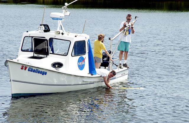 NASA image: KENNEDY SPACE CENTER, FLA.  -  A research team member aboard one of the watercraft being utilized to conduct underwater acoustic research in the Launch Complex 39 turn basin releases some of the project's equipment into the water.  Several government agencies, including NASA, NOAA, the Navy, the Coast Guard, and the Florida Fish and Wildlife Commission are involved in the testing. The research involves demonstrations of passive and active sensor technologies, with applications in fields ranging from marine biological research to homeland security. The work is also serving as a pilot project to assess the cooperation between the agencies involved. Equipment under development includes a passive acoustic monitor developed by NASA’s Jet Propulsion Laboratory, and mobile robotic sensors from the Navy’s Mobile Diving and Salvage Unit.