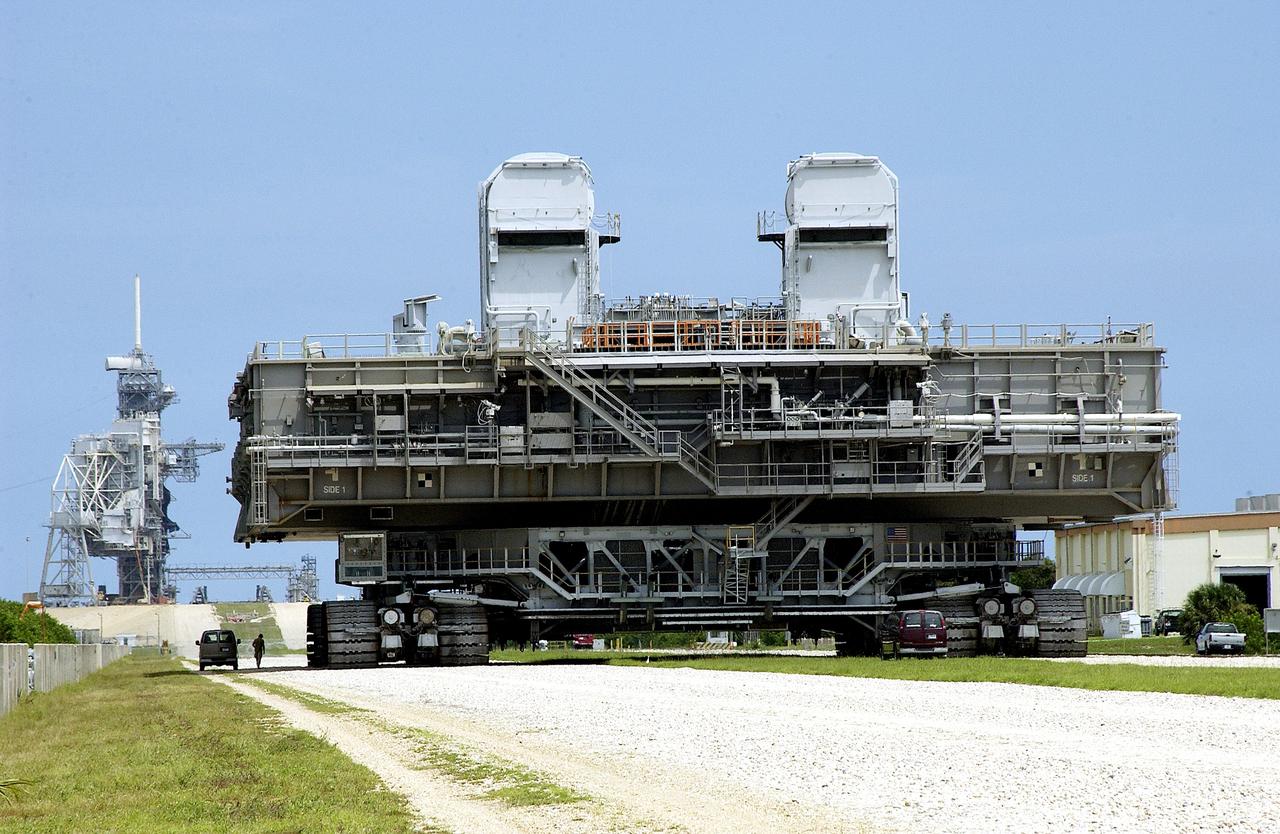 KENNEDY SPACE CENTER, FLA.  -   Crawler-transporter (CT) number 2 nears the launch pad with a Mobile Launcher Platform (MLP) on top.  After recent modifications to the cab and muffler system, the CT was taken on a test run.   The CT moves Space Shuttle vehicles, situated on the MLP, between the VAB and launch pad.  Moving on four double-tracked crawlers, the CT uses a laser guidance system and a leveling system for the journey that keeps the top of a Space Shuttle vertical within plus- or minus-10 minutes of arc.  The system enables the CT-MLP-Shuttle to negotiate the ramp leading to the launch pads and keep the load level.  Unloaded, the CT weighs 6 million pounds.  Seen on top of the MLP are two tail service masts that support the fluid, gas and electrical requirements of the orbiter’s liquid oxygen and liquid hydrogen aft umbilicals.