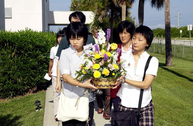 NASA image: KENNEDY SPACE CENTER, FLA.  -    Japanese girls from Urawa Daiichi Girls High School, Urawa, Japan, carry a floral tribute to the crew of Columbia to place at the STS-107 memorial stone at the Spacehab facility, Cape Canaveral, Fla.   The group was  awarded the trip to Florida when their experiments were chosen to fly on mission STS-107.  The group was also meeting with American students from Melbourne and Jacksonville, Fla.   The National Space Development  Agency of Japan (NASDA) and the KSC International Space Station and Payloads Processing Directorate worked with the NASA KSC Education Programs and University Research Division to coordinate the students’ visit.