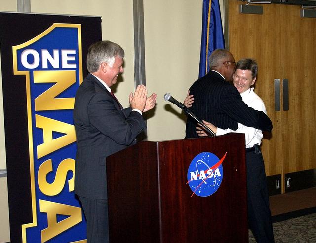 NASA image: KENNEDY SPACE CENTER, FLA.  -   At the rollout of the One NASA initiative at KSC, Glenn Research Center Director Dr. Julian Earls embraces implementation team lead Johnny Stevenson while KSC Director Jim Kennedy (left) applauds.  Earls gave a motivational speech during the luncheon held at the Visitor Complex Debus Conference Center.  The event was held at the IMAX Theater® where NASA leaders discussed One NASA with selected employees.  Explaining how their respective centers contribute to One NASA, along with Kennedy and Earls, were James Jennings,  NASA’s associate deputy administrator for institutions and asset management; Ed Weiler, associate administrator for Space Science; Kevin Peterson, Dryden Flight Research Center director; incoming KSC Deputy Director Woodrow Whitlow; and implementation team lead Johnny Stevenson.