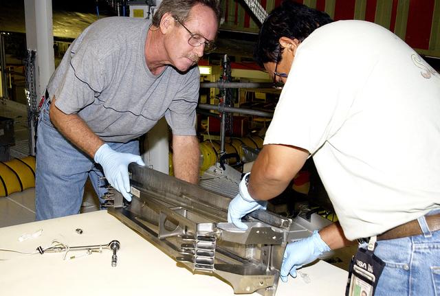 NASA image: KENNEDY SPACE CENTER, FLA. - Technician Saul Ngy, with United Space Alliance, prepares to install a spar on the wing of the orbiter Atlantis.  The Reinforced Carbon Carbon (RCC) panels are mechanically attached to the wing with a series of floating joints - spars - to reduce loading on the panels caused by wing deflections. The aluminum and the metallic attachments are protected from exceeding temperature limits by internal insulation.