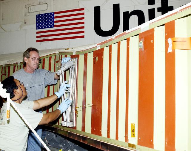 NASA image: KENNEDY SPACE CENTER, FLA. -  Mike Hyatt (left) and Saul Ngy, technicians with United Space Alliance, prepare to install a spar on the wing of the orbiter Atlantis.  The Reinforced Carbon Carbon (RCC) panels are mechanically attached to the wing with a series of floating joints - spars - to reduce loading on the panels caused by wing deflections. The aluminum and the metallic attachments are protected from exceeding temperature limits by internal insulation.