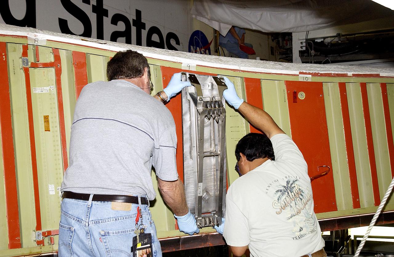 KENNEDY SPACE CENTER, FLA. -  Mike Hyatt (left) and Saul Ngy, technicians with United Space Alliance, install a spar on the wing of the orbiter Atlantis.  The Reinforced Carbon Carbon (RCC) panels are mechanically attached to the wing with a series of floating joints - spars - to reduce loading on the panels caused by wing deflections. The aluminum and the metallic attachments are protected from exceeding temperature limits by internal insulation.